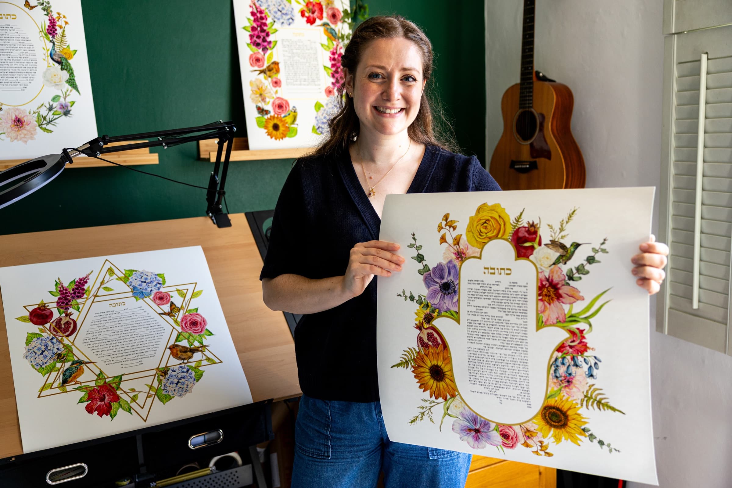 Sophie Bacall in her studio holding a hand-painted Hamsa Blossom ketubah