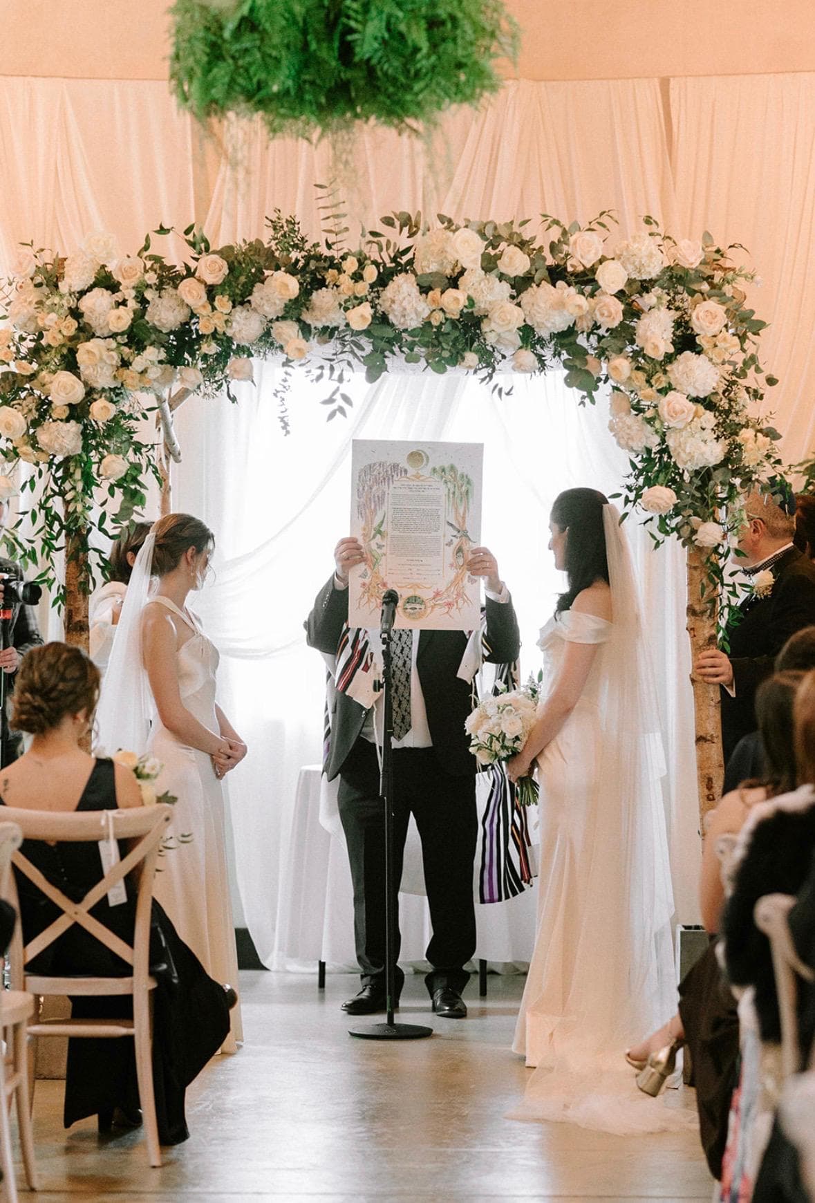 Chloe and Jade standing beneath their chuppah with their hand-painted custom ketubah