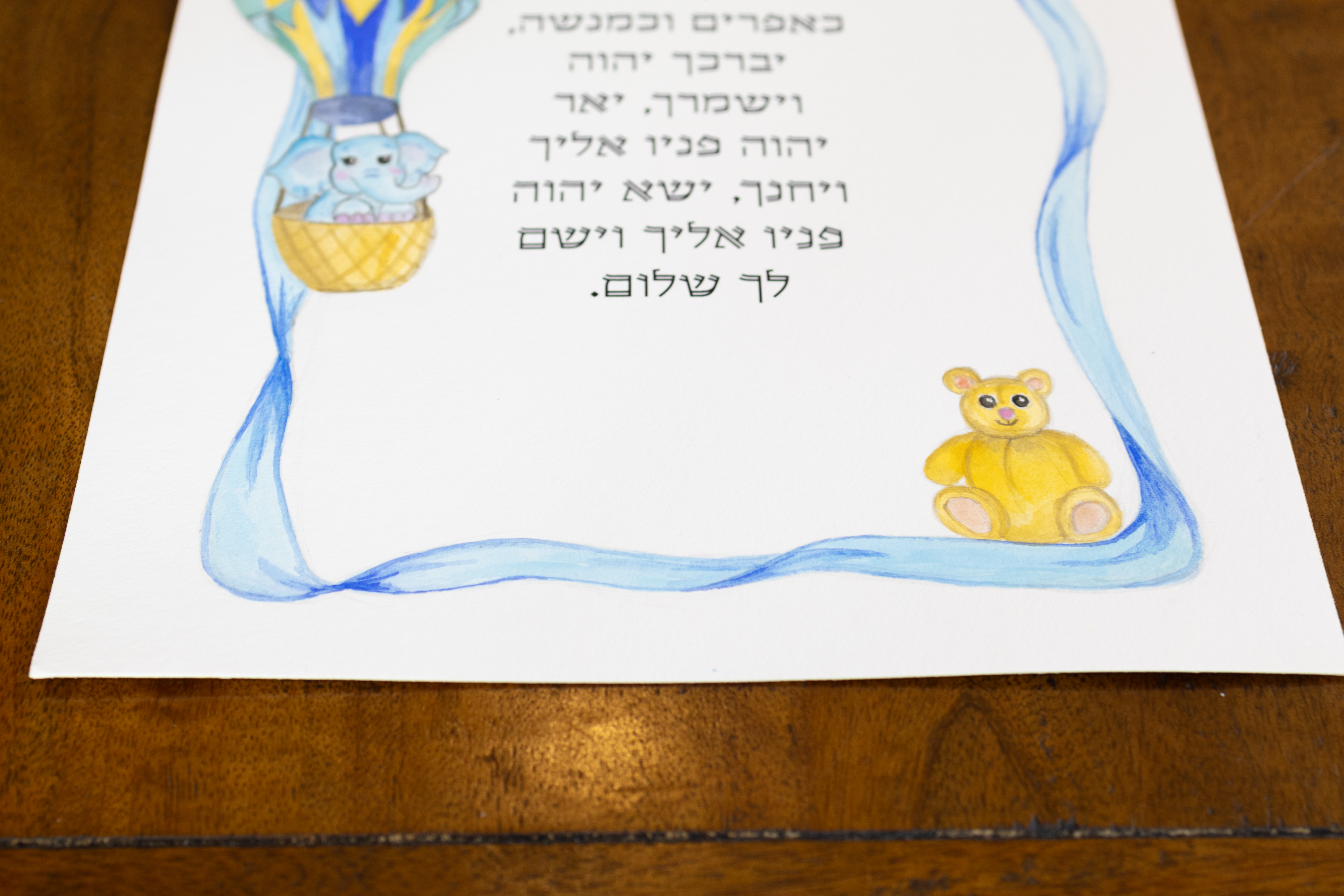 פרט של הפילון, הדובון והסרט הכחול בהדפס ברכת הבנים לילד