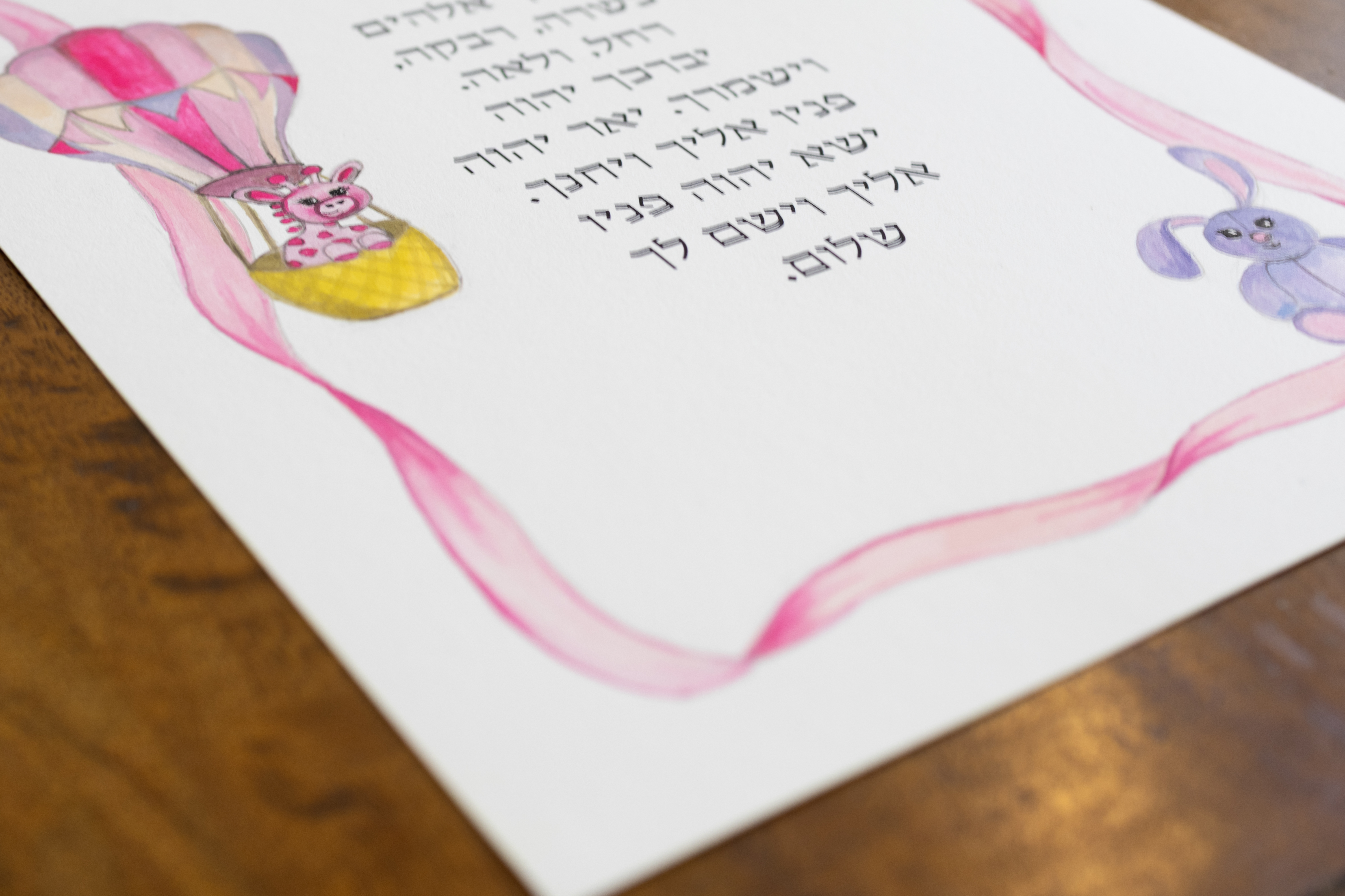 פרט של הג׳ירפה, הארנבת והסרט הוורוד בהדפס ברכת הבנות לילדה