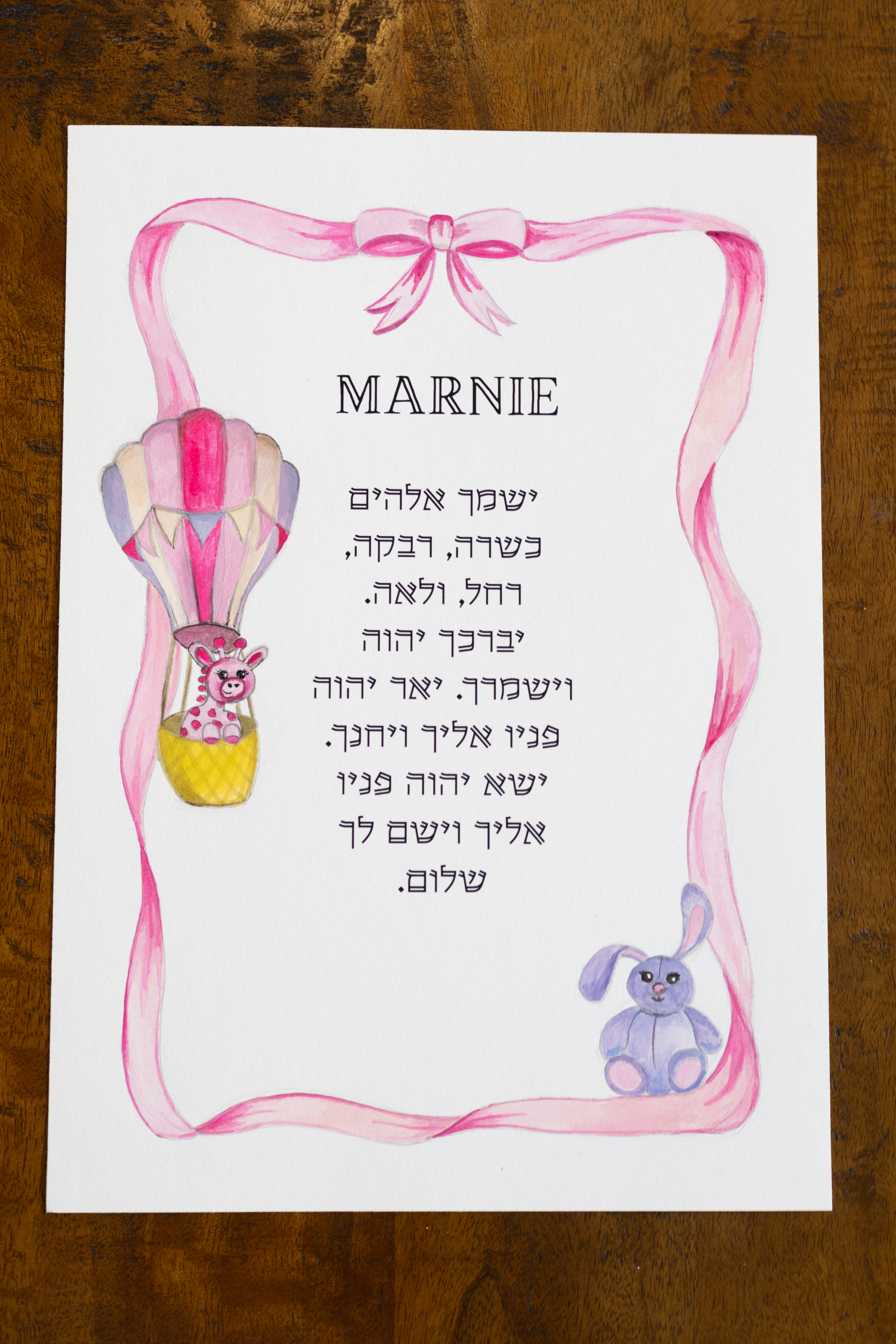הדפס מוגמר ואישי של ברכת הבנות לילדה, מוצג על שולחן עץ