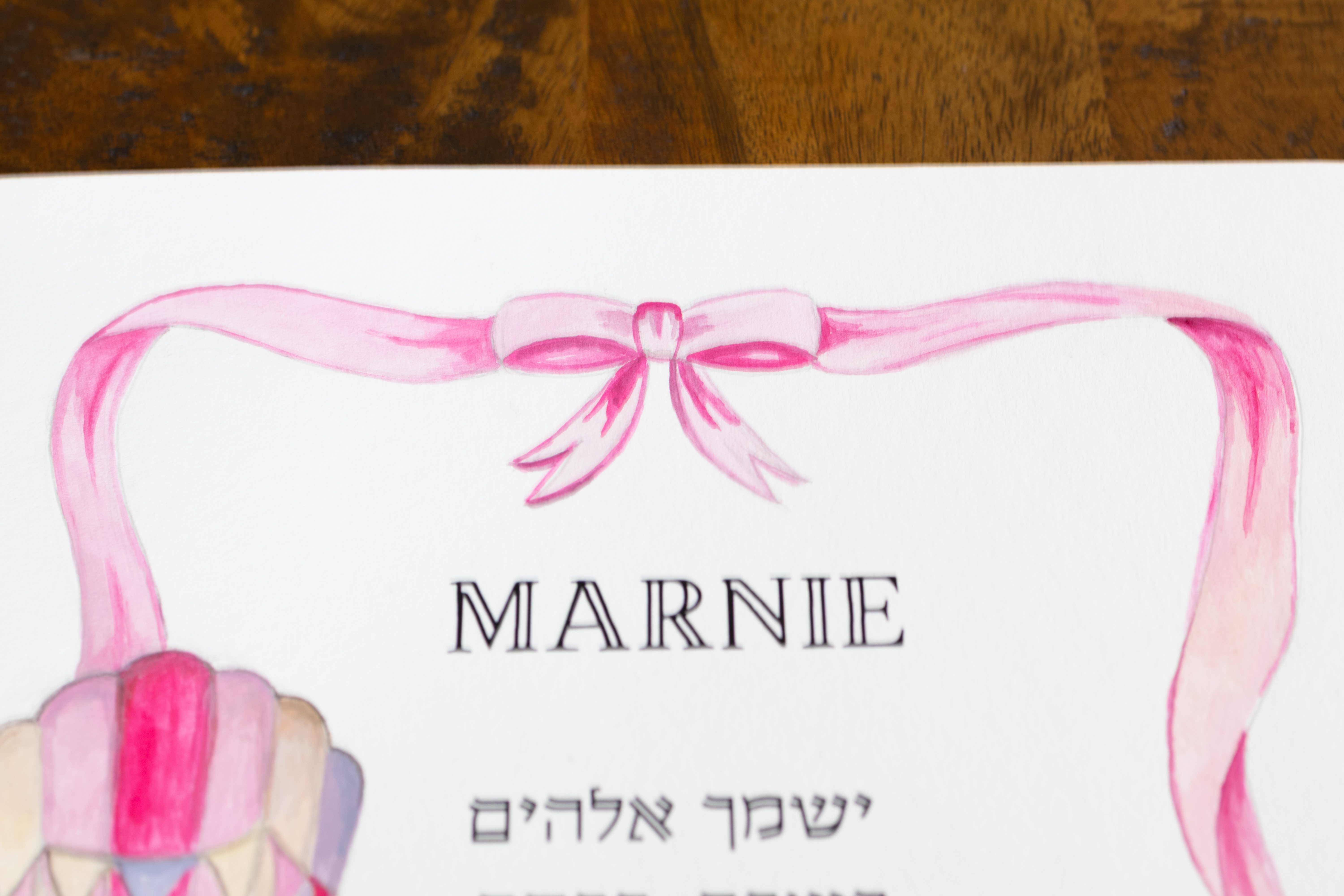 תקריב של השם האישי והסרט הוורוד בהדפס ברכת הבנות לילדה